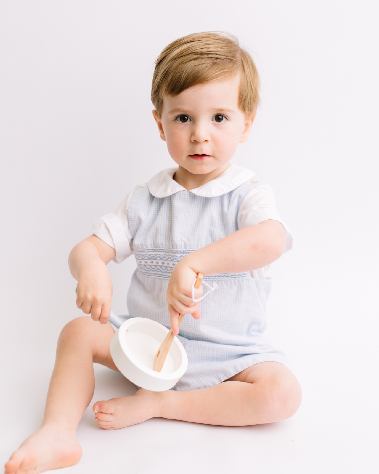 photographing a toddler with the help of indoor kitchen toys.